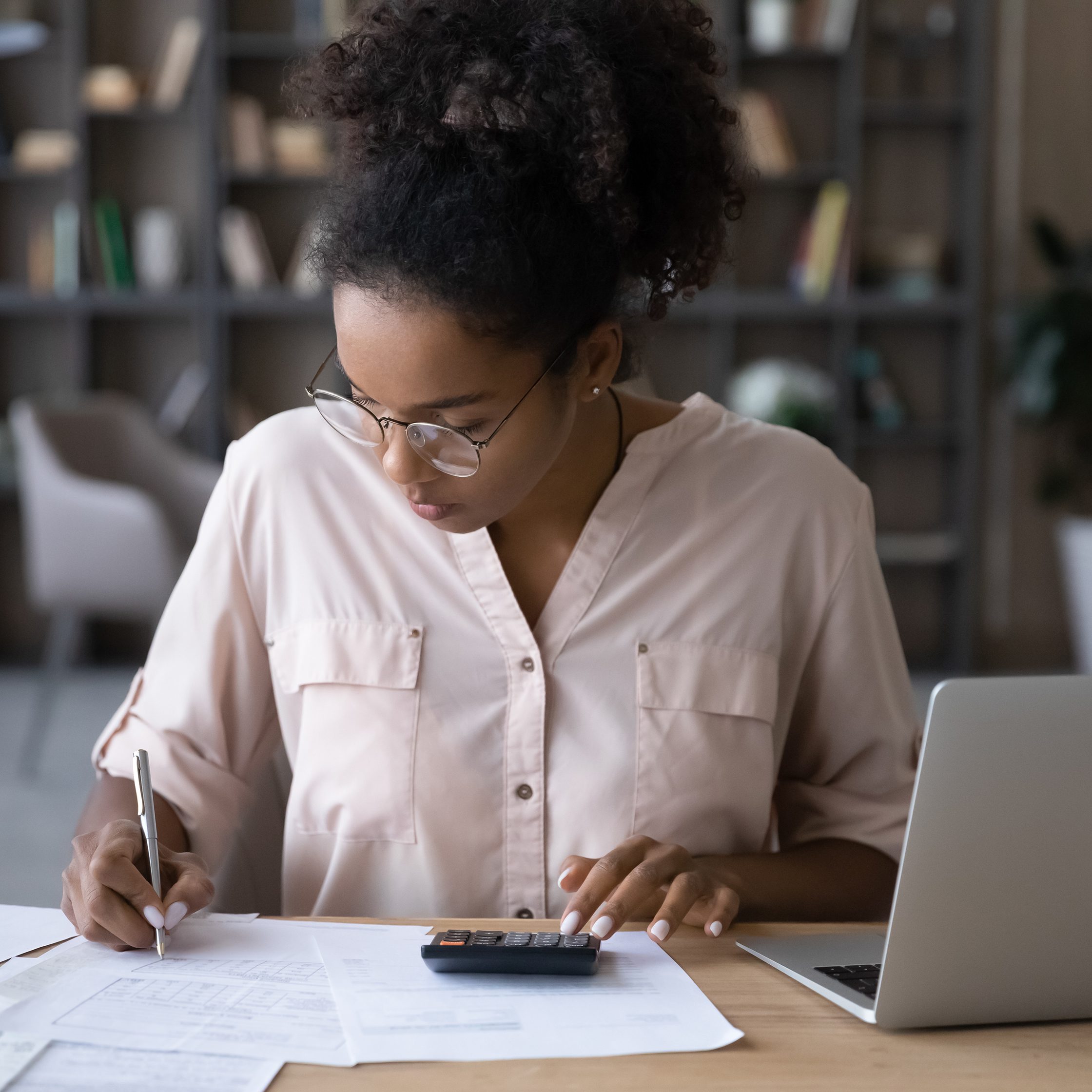 undergraduate accounting programs; Serious young biracial woman sit at desk undergraduate programs in accounting online on laptop. 