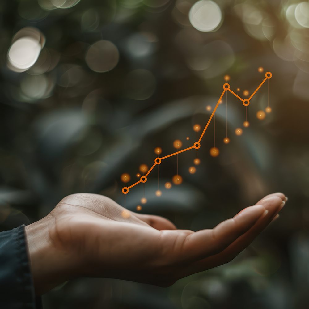 Undergraduate programs in Economics, Business Administration concentration. A person is holding up a upward-trending graph symbolizing financial success or positive performance metrics