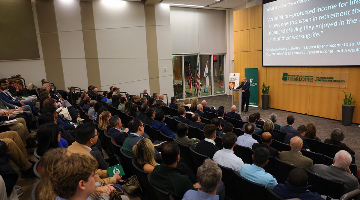 Professor Robert C. Merton presents to a full auditorium during the Mathematical Finance 20th anniversary event at The Dubois Center at UNC Charlotte Center City.
